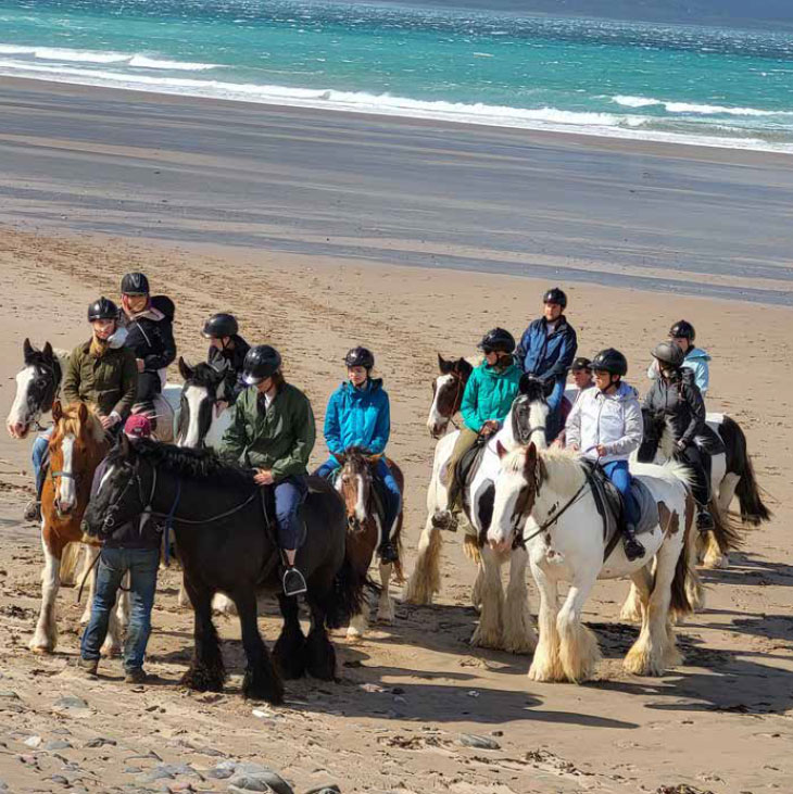 Students horseriding on beach